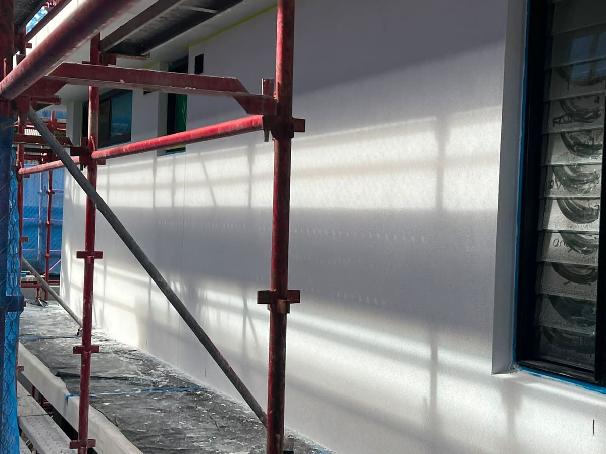Acrylic texture rendered facade on a Sydney building viewed through the scaffolding during the final coat