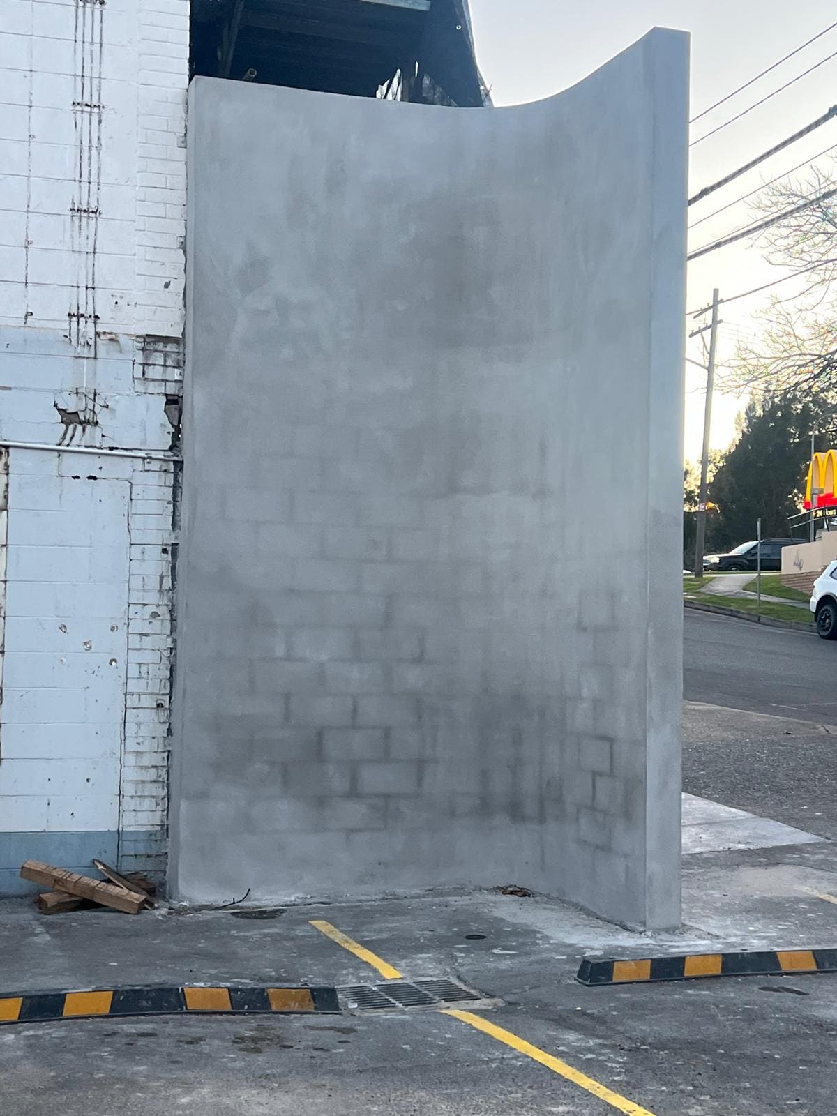 Tall curved feature wall rendered in smooth grey cement at a Sydney commercial site