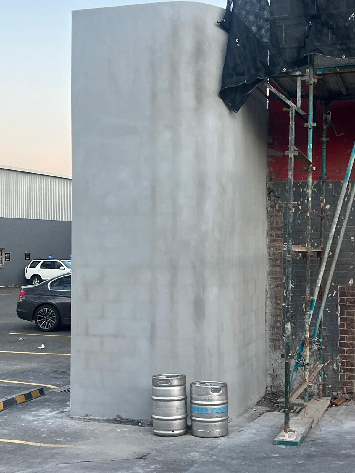 Curved rendered wall on a Sydney commercial building with scaffolding against the original brickwork behind