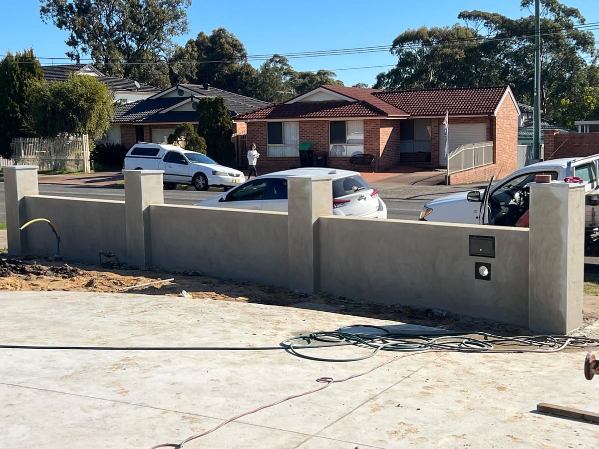 Grey rendered boundary fence along the front of a Sydney property with piers and a letterbox