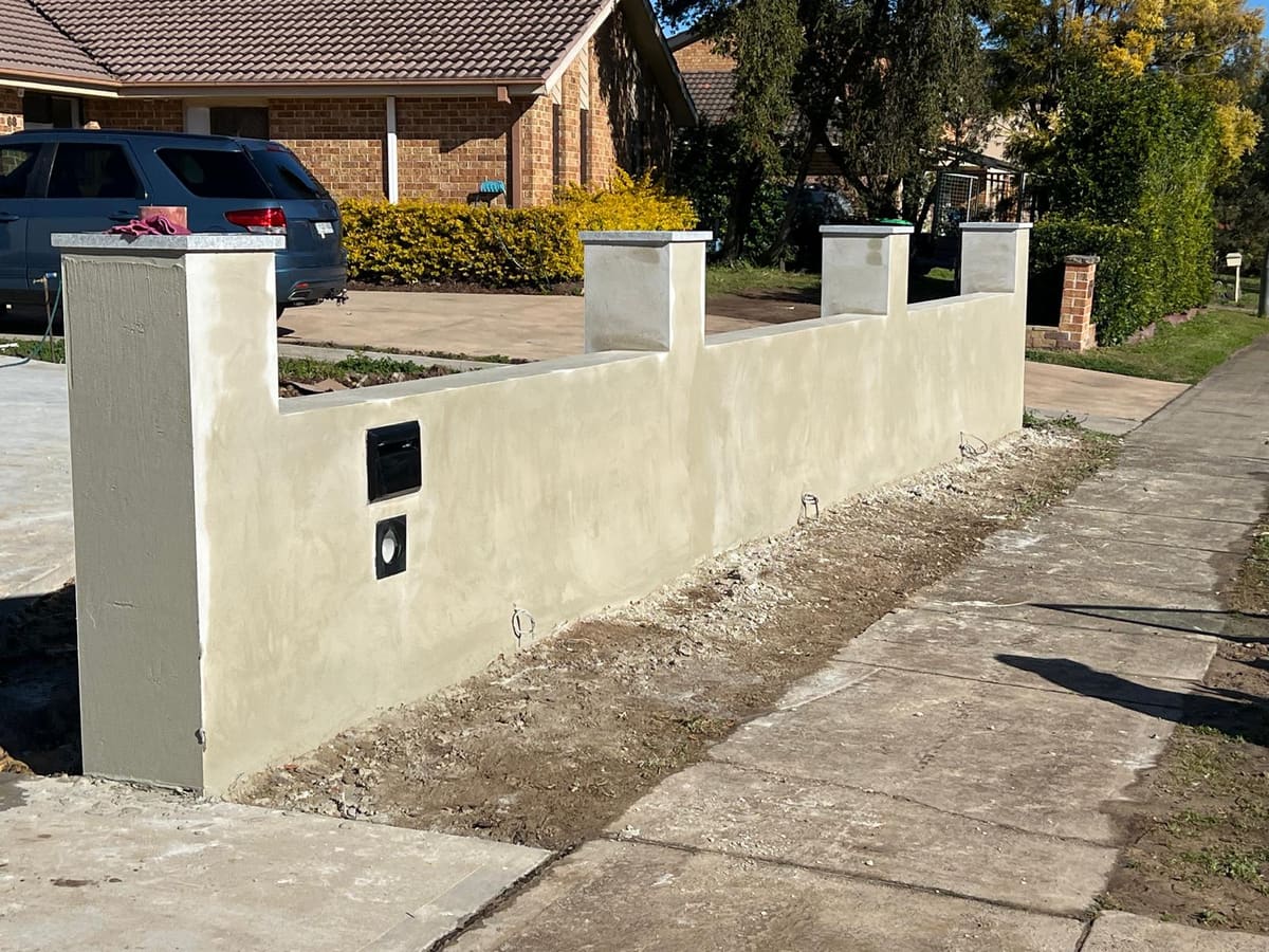 Cream rendered front fence with capped piers and a built in letterbox at a Sydney home