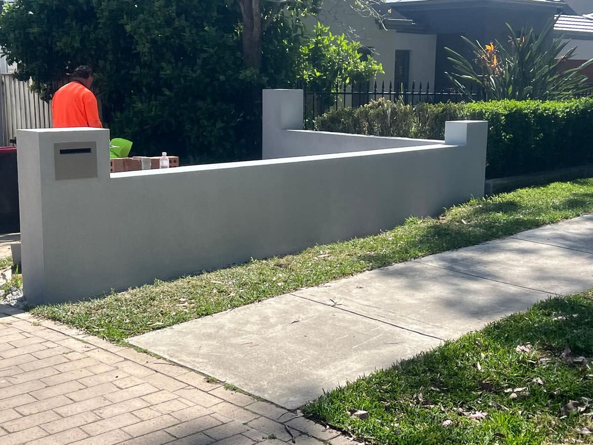 Smooth grey rendered front wall with an integrated letterbox at a Sydney home