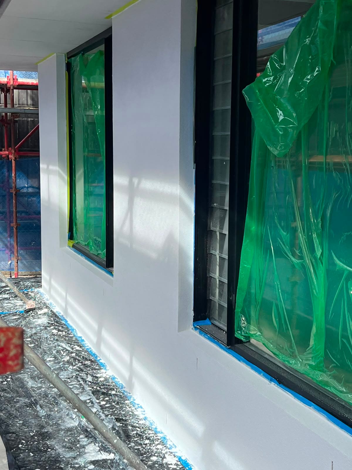 Crisp white rendered window reveals on a Sydney new build with the glazing masked off during texture coating